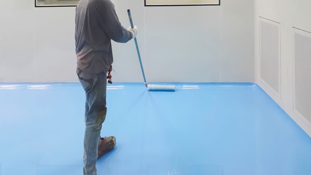 Man Applying Epoxy Flooring In A Room